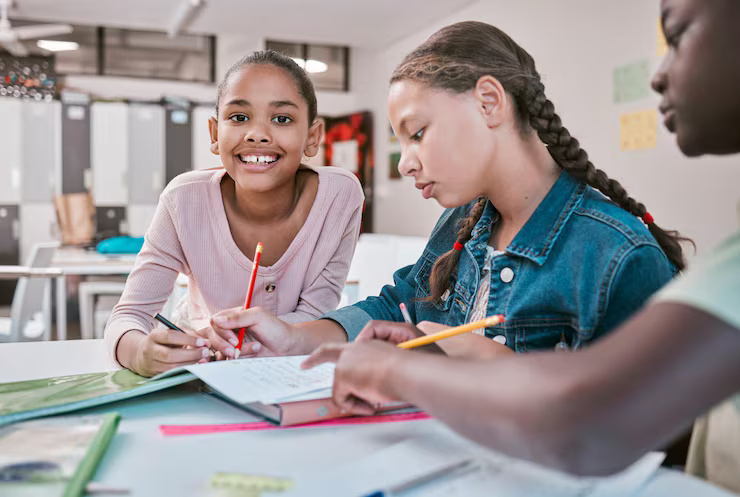 A photo of a classroom of students learning how to read and write. One girl is smiling at the camera 